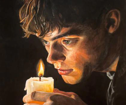 A young man gazes intently at a flickering candle, his face illuminated by its warm glow in a powerful study of light, focus, and introspection.