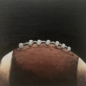 Tiny Football (2024) by Ben Young This painting by Ben Young is a close up oil painting of an american football ball.
